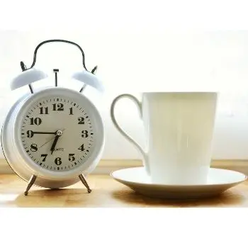 drinking coffee with alarm clock in morning